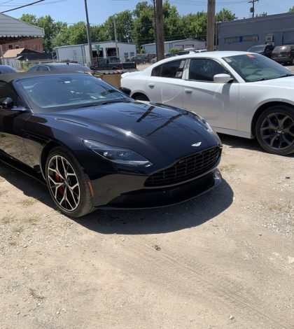 Two black sports cars parked in front of a modern building, showcasing sleek designs and polished exteriors.