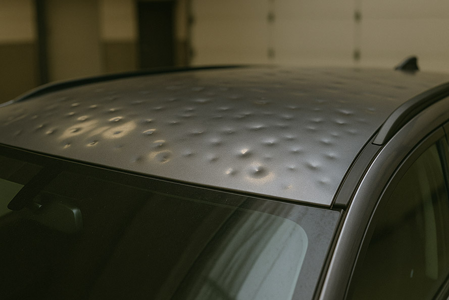 Vehicle roof showing several hail dents before repair.